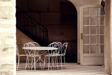White table with six wrought iron chairs next to the stairs and a wooden white door