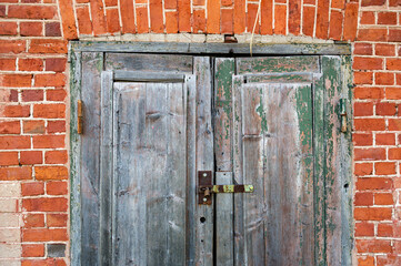Old wooden door in front of a red brick wall