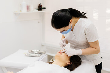 The procedure for lip augmentation and correction in a cosmetology salon. The specialist gives an injection to the patient's lips. Concept of cosmetology, cosmetic injections, and cosmetic surgery.