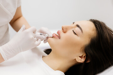 Injection lip augmentation. Close-up of beautician's hands doing cosmetic procedures for sexy...
