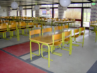 Empty classroom with desks and chairs and large windows at school. 