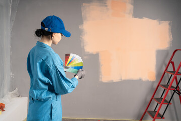 house painter girl decorator choose the color using the sample swatch. House to renovate