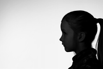 Silhouette of dark person profile on light background.