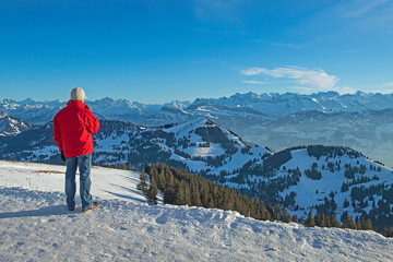 Tourist geniesst die Aussicht von Rigi-Kulm auf die verschneite Gebirgslandschaft, Schweiz