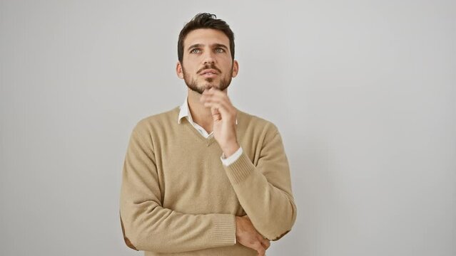 Portrait of a young, bearded hispanic man, bored and stressed. he's standing, arms crossed, wearing a sweater. he looks tired, thinking about his depression problems on a white, isolated background.