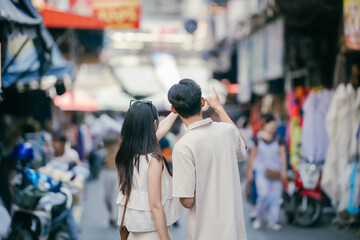 Young excited Asian couple visiting local market together, travel concept.