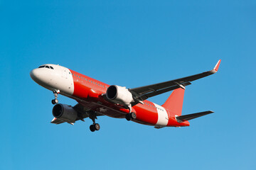 Passenger red and white colours airplane landing gear flying in the clear blue sky