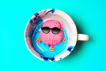 Brain in Sunglasses Floating on Inflatable Ring in Coffee Cup