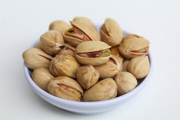 Salted pistachio on the small white bowl, isolated on white background