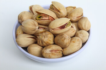 Salted pistachio on the small white bowl, isolated on white background