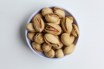 Salted pistachio on the small white bowl, isolated on white background, flat lay or top view