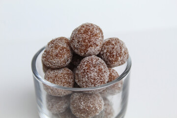 Tamarind candies in small glass. Sweet and sour candy made from tamarind paste and coated by sugar. Isolated on white background