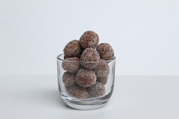 Tamarind candies in small glass. Sweet and sour candy made from tamarind paste and coated by sugar. Isolated on white background