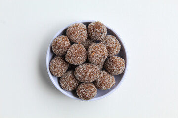 Tamarind candy balls in white bowl. Isolated on white background, flat lay or top view