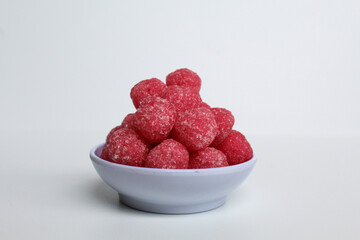 Soursop candy, in pink color and ball shaped, coated by sugar. Isolated on white background