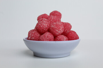 Soursop candy, in pink color and ball shaped, coated by sugar. Isolated on white background