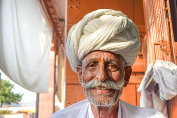 Elderly man with mustache and traditional Rajasthani turban smiling to camera