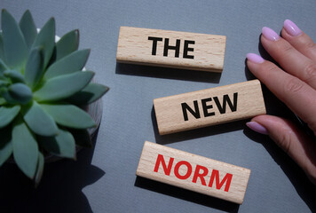The new norm symbol. Concept words The new norm on wooden blocks. Beautiful grey background with...