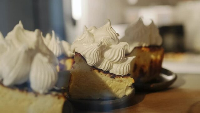 Pieces of cheesecake decorated with meringue lie on a display in a coffee shop. Basque cheesecake closeup, desserts, bakery.