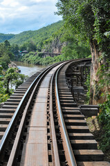 Fototapeta premium Tham Krasae Pass. A huge wooden trestle supports the tracks on a cliff bordered on one side by the mountain and on the other by the River Kwai