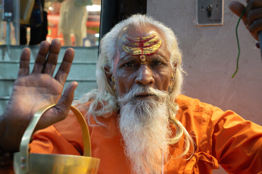 Ascetic monk Sadhu in India with beard, white hair and painted face preaching