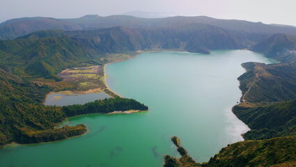 Aerial volcanic island lagoon in morning. Rippling turquoise water wash rocky