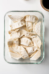raw frozen gyozas in glass box food top view