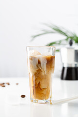 glass with cold coffee and ice cubes and milk