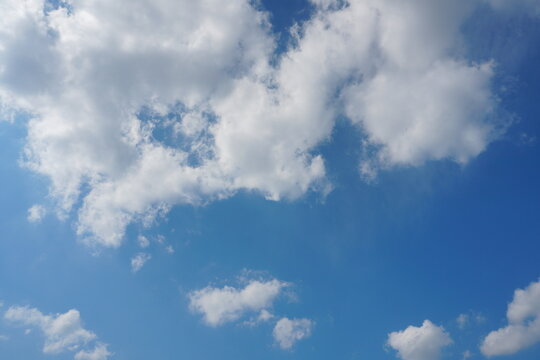 White fluffy clouds in the sky. Blue sky and cloud cover on a sunny summer day. Empty background, copy space
