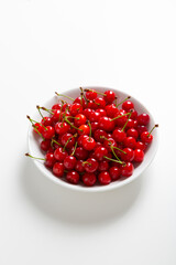 ripe red cherries in a white bowl close up on light surface