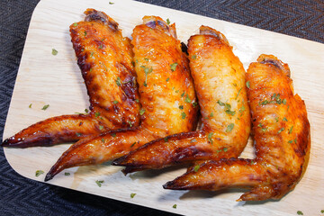 Grilled chicken wings on a wooden board.