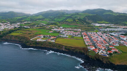 Fototapeta na wymiar Aerial green cape landscape on cloudy day. Drone flight over dark ocean water