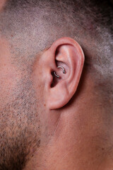 Outer ear black tragus piercing on adult white man