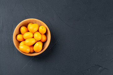 Kumquat fruit in a bowl on a dark background
