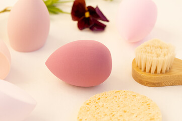 Fototapeta na wymiar Beauty blender, beauty sponge on a beige background. Bright sponges for make-up cosmetics, a wooden brush for face massage. Makeup products. Beauty concept. Place for text.