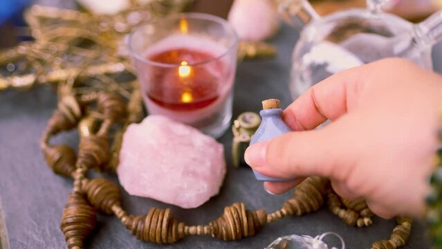 spiritualistic session in salon of soothsayer, fortune-teller, hands of female medium, alchemist, herbalist hold witchcraft potion, poison, elixir of youth, burning candles, spells, ritual magic