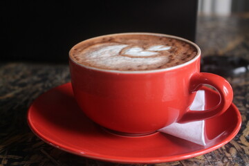 photo of a glass of latte coffee in a red glass with a white tissue