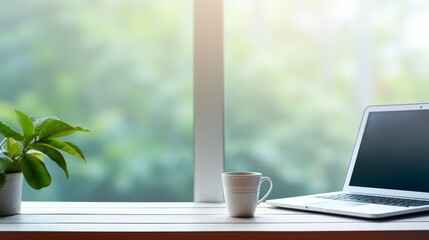 Laptop computer and coffee cup on wooden table with green nature background