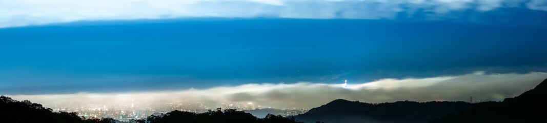Moving clouds make the city's night scene appear and disappear. Full of mystery. Enjoy the night view of Taipei City from Xindian Mountain. Taiwan.