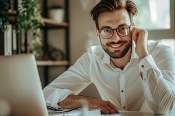 Portrait of a smiling and successful young man sitting in the office at a desk and working on a laptop and with documents. He looks at the camera while holding the glasses on his face, Generative AI