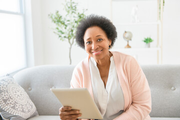 Black woman using tablet on living room at home