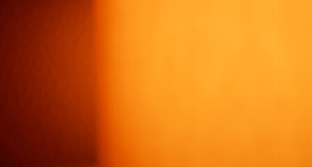Blurred image of a nighttime lamp with light reflecting off a wall. Close-up and blurry image of a lamp at night with orange color. Orange-yellow light of the gradient and abstract background.