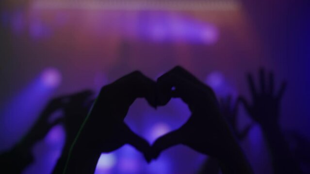Heart Hands Silhouette at a Concert with Vibrant Stage Lights