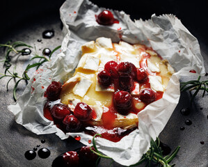 Melted baked Camembert cheese with cranberry sauce, close up view