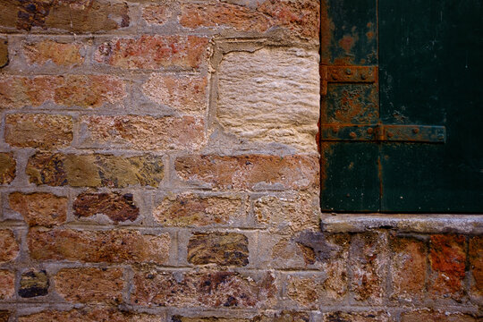 Alte Mauer mit rostigem Fensterladen.