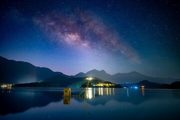 Beautiful view of the Milky Way from the pier on the lakeside of the mountains. Sun Moon Lake is...