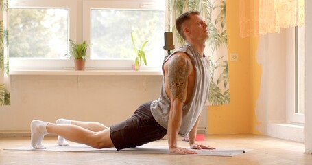 Strong Athletic Fit Man doing yoga exercise. Home workouts provide individuals with the flexibility...
