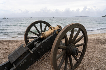 Historical reenactment of events. Cannon from the time of Napoleon Bonaparte on the beach against the backdrop of the sea and clouds.