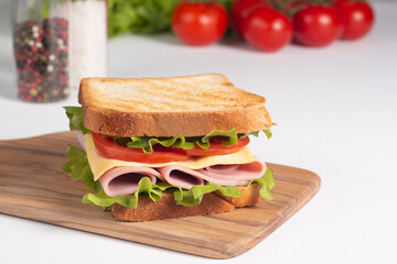 Close-up of two sandwiches with bacon, salami, prosciutto and fresh vegetables on rustic wooden cutting board. Club sandwich concept - 752430722
