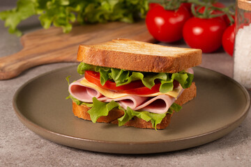 Close-up of two sandwiches with bacon, salami, prosciutto and fresh vegetables on rustic wooden cutting board. Club sandwich concept - 752430926